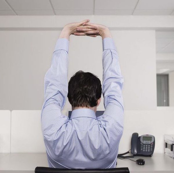 A man stretching at his desk