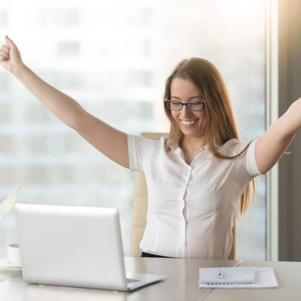 a woman celebrating in front of a laptop