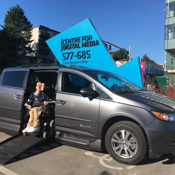 David emerging from his modified van outside his workplace