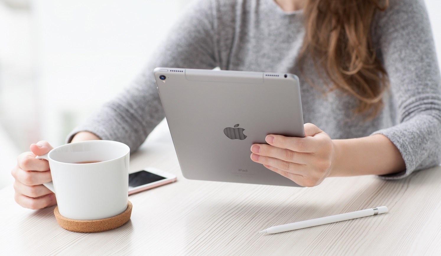 A woman with an iPad in one hand and a cup of coffee in the other