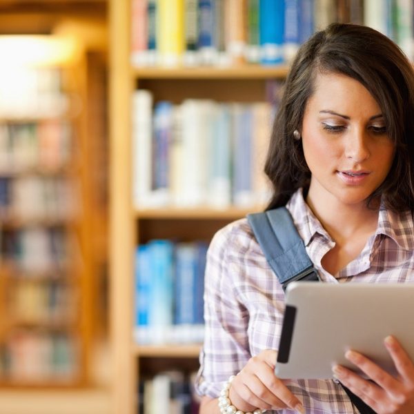 A woman using a tablet in a library