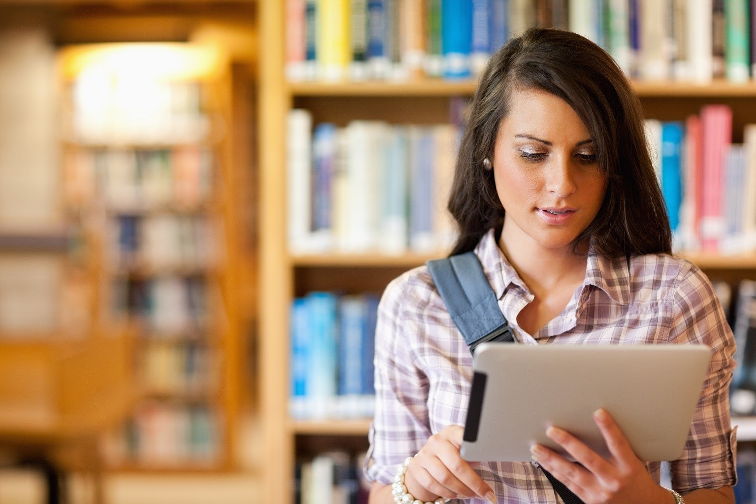 A woman using a tablet in a library