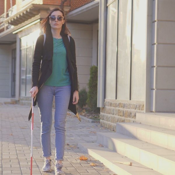 A woman walking on the street using a white cane