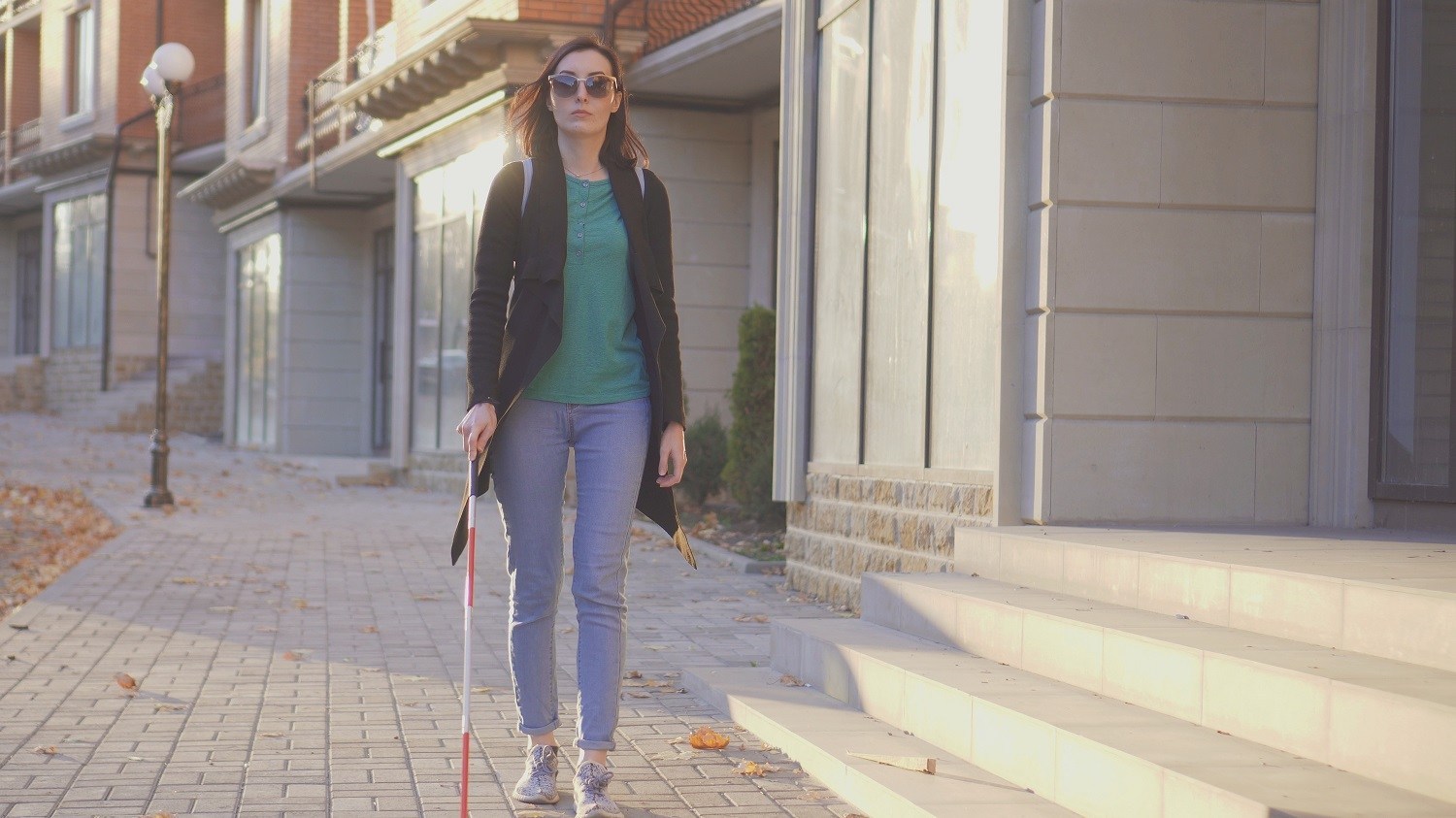 A woman walking on the street using a white cane