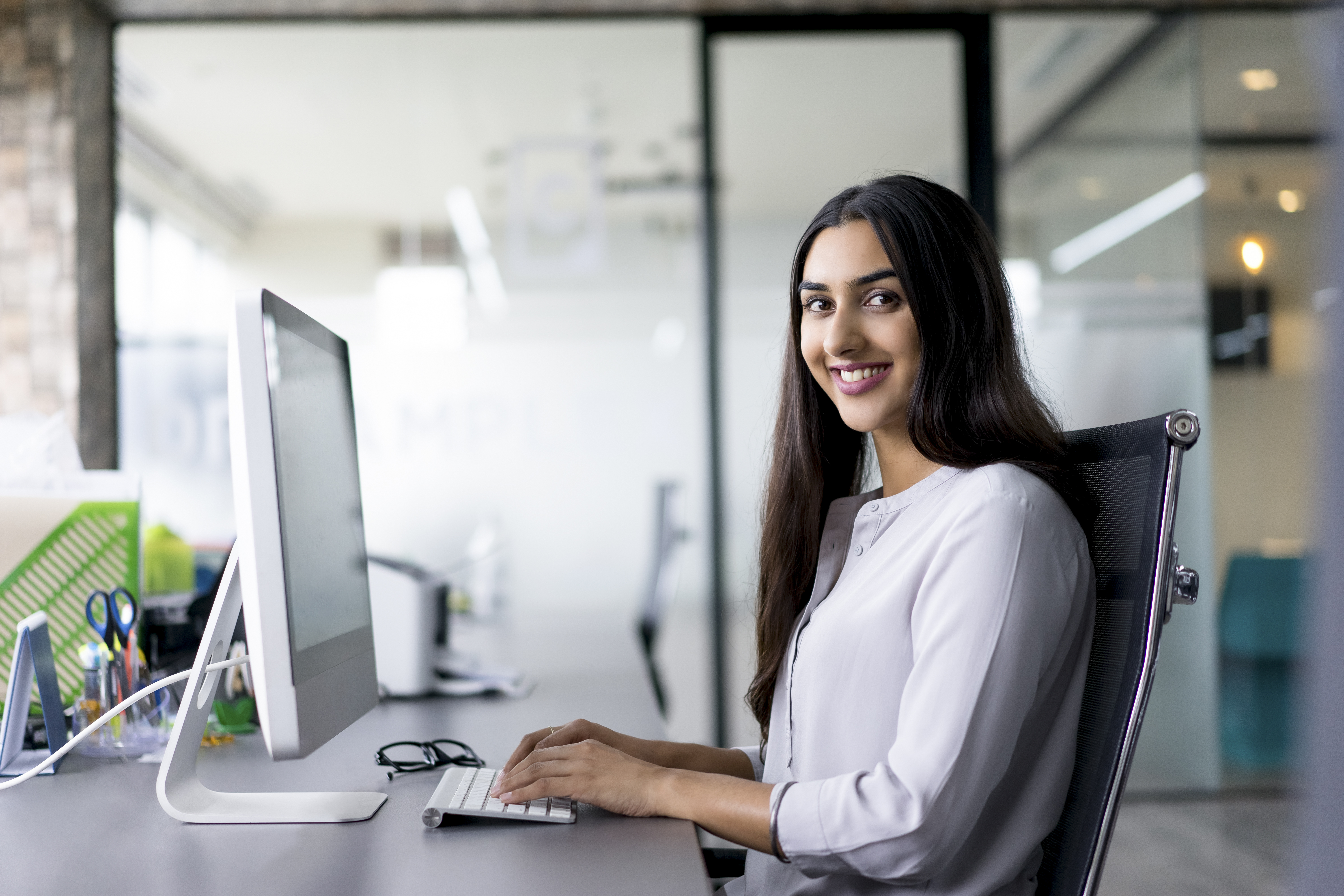 a woman smiling while working on a computer