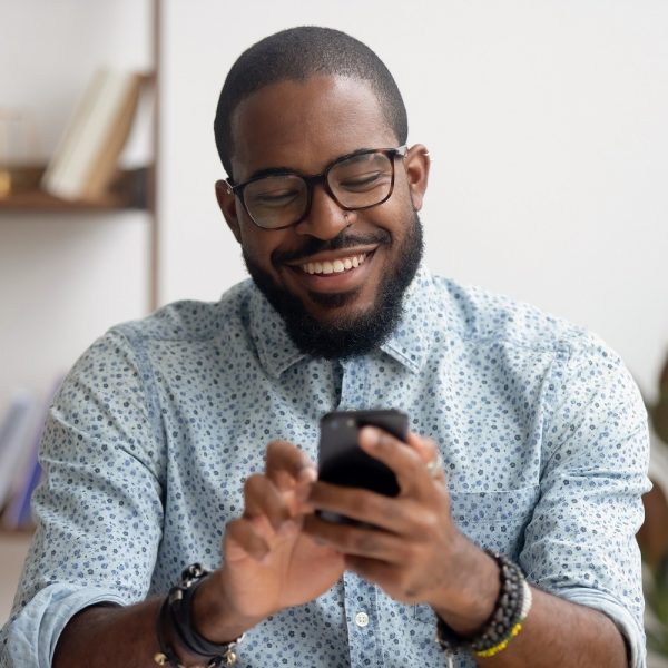 man smiling and using his smartphone