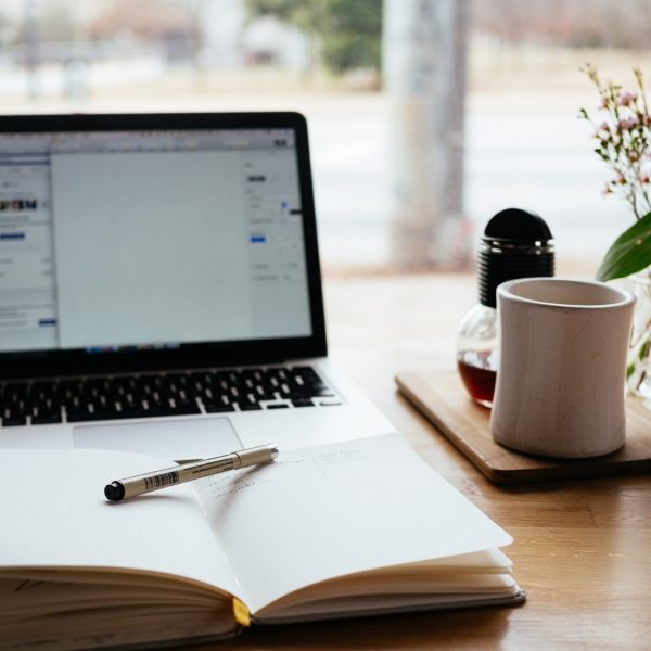 a laptop with a notebook and pen in front of it