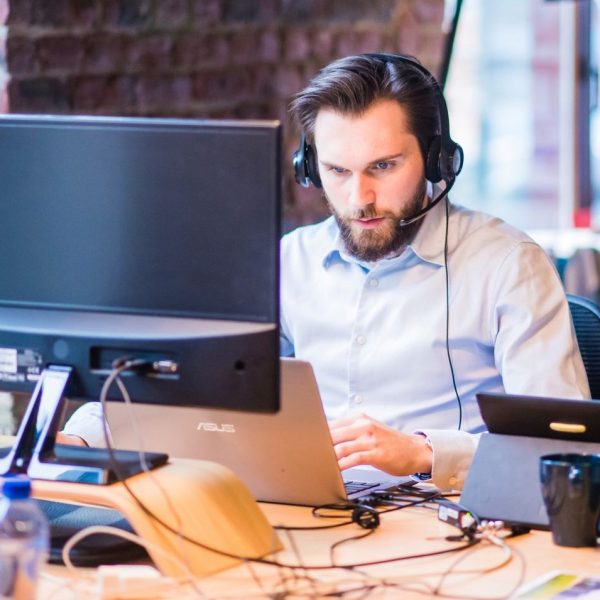 man working at his laptop, wearing headphones