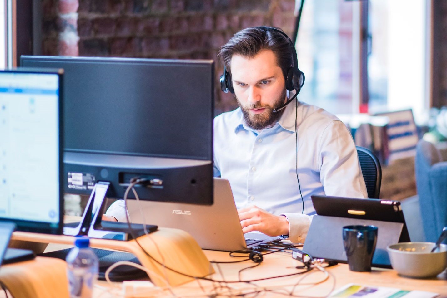 man working at his laptop, wearing headphones