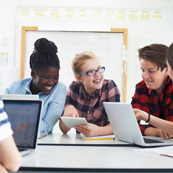 Five students around table talking and smiling