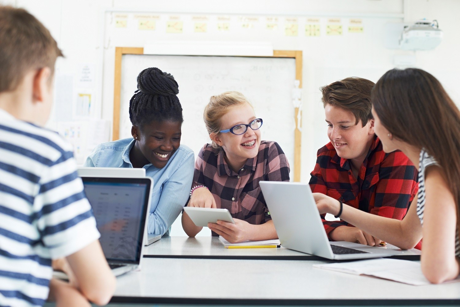 Five students around table talking and smiling