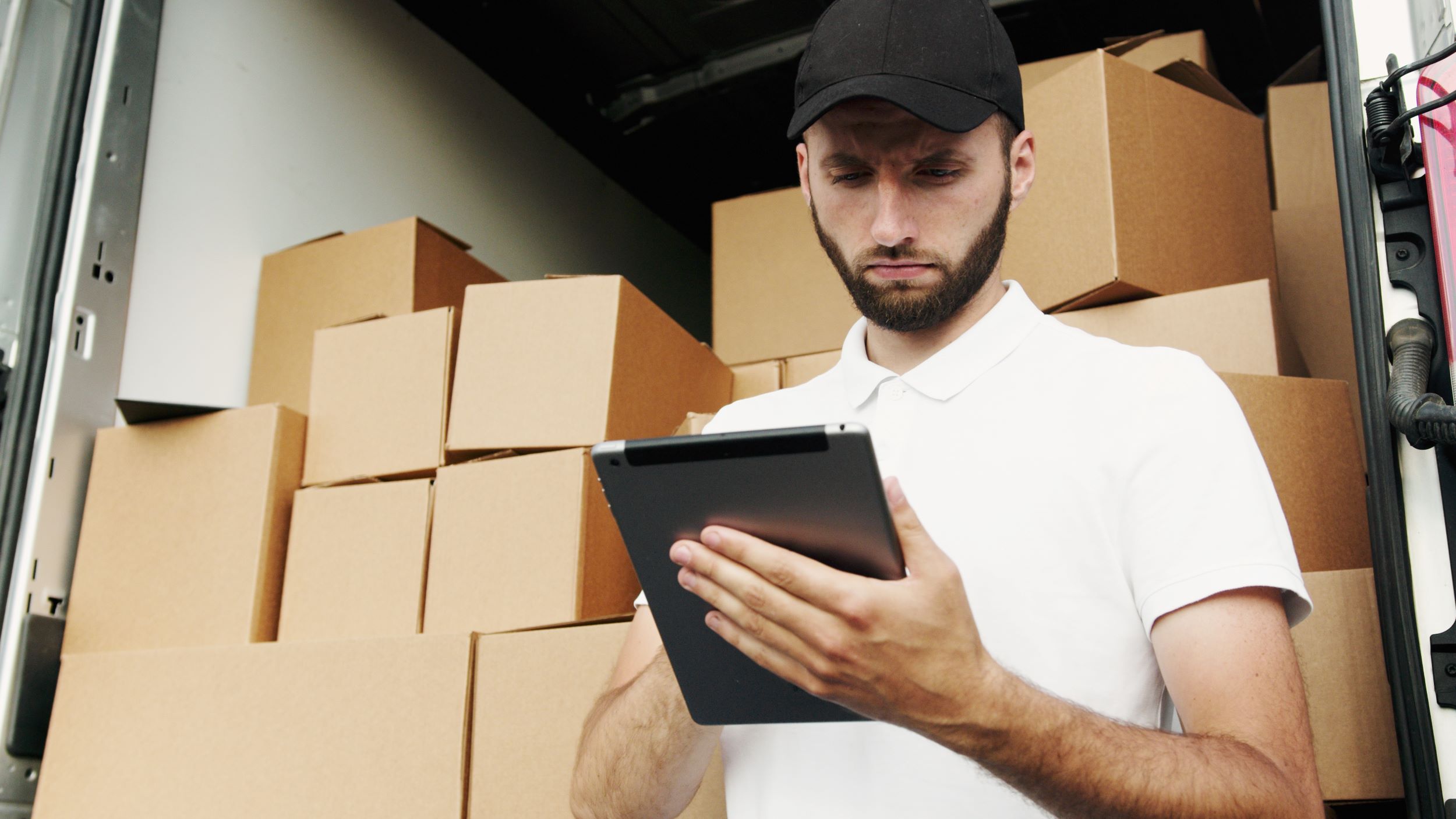 man using a tablet; piles of boxes behind him