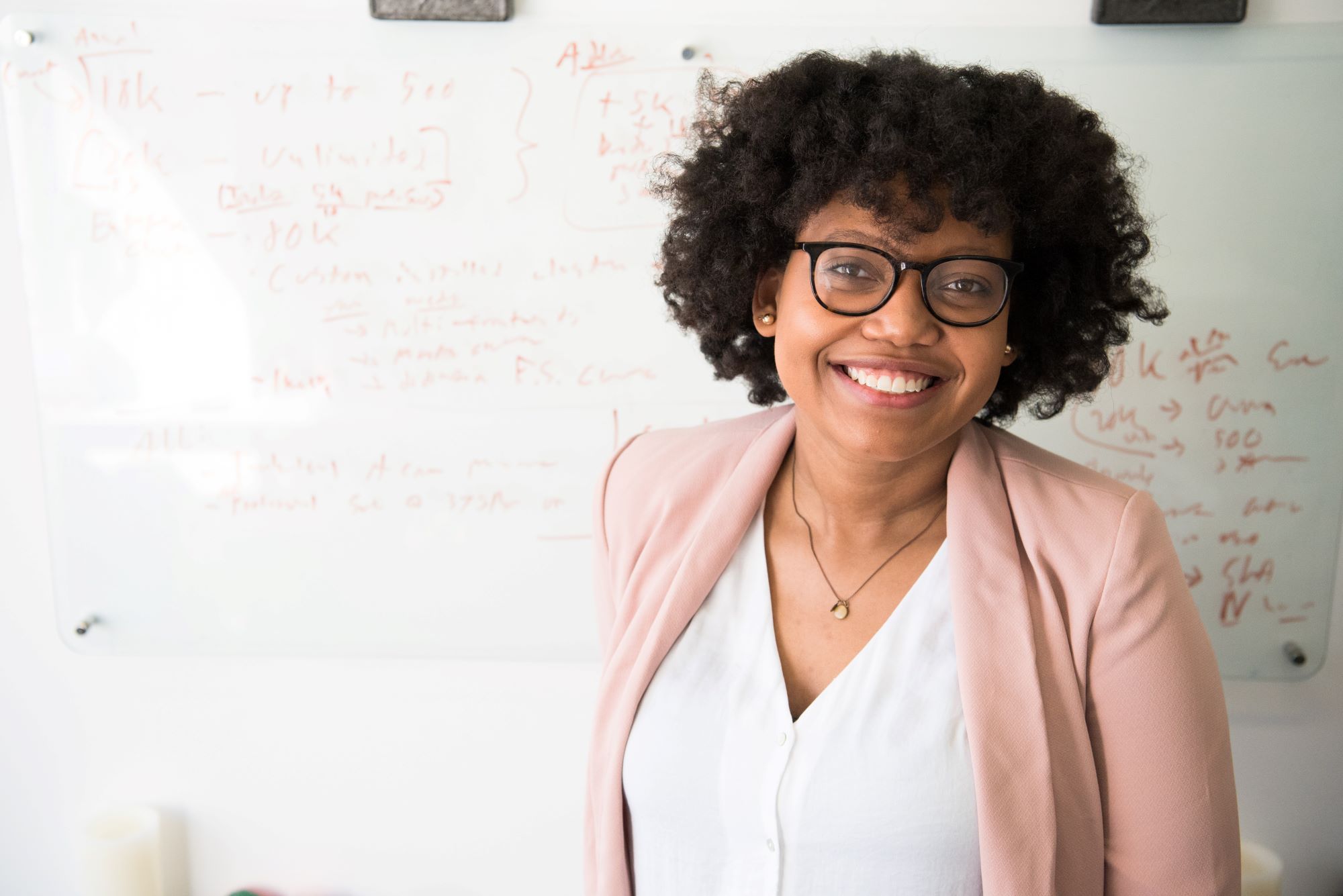 woman smiling; behind her is a whiteboard