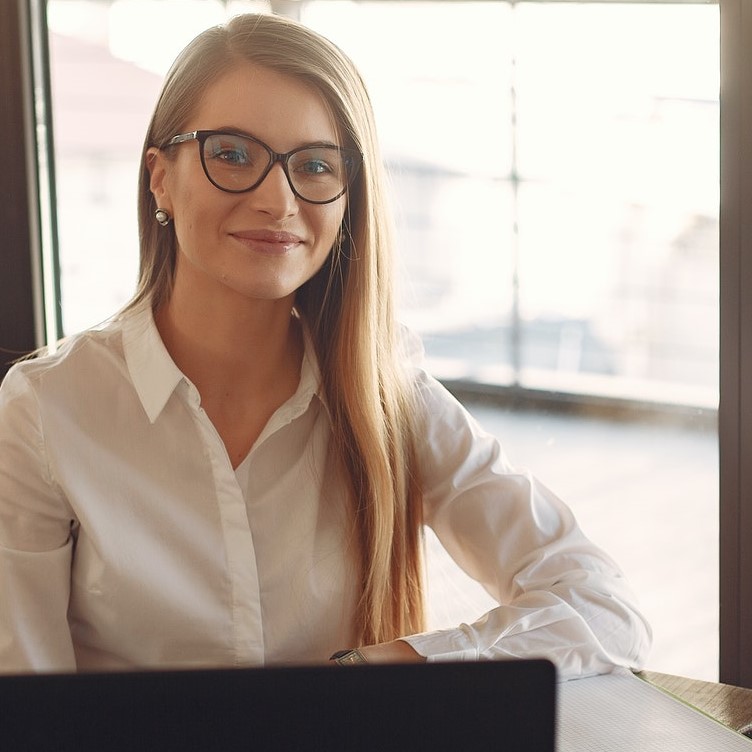 woman smiling, seated at desk