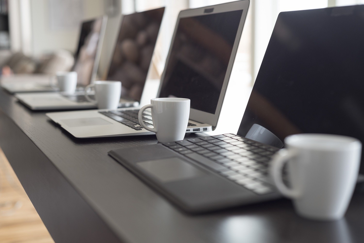 A number of laptops placed in a row on a desk