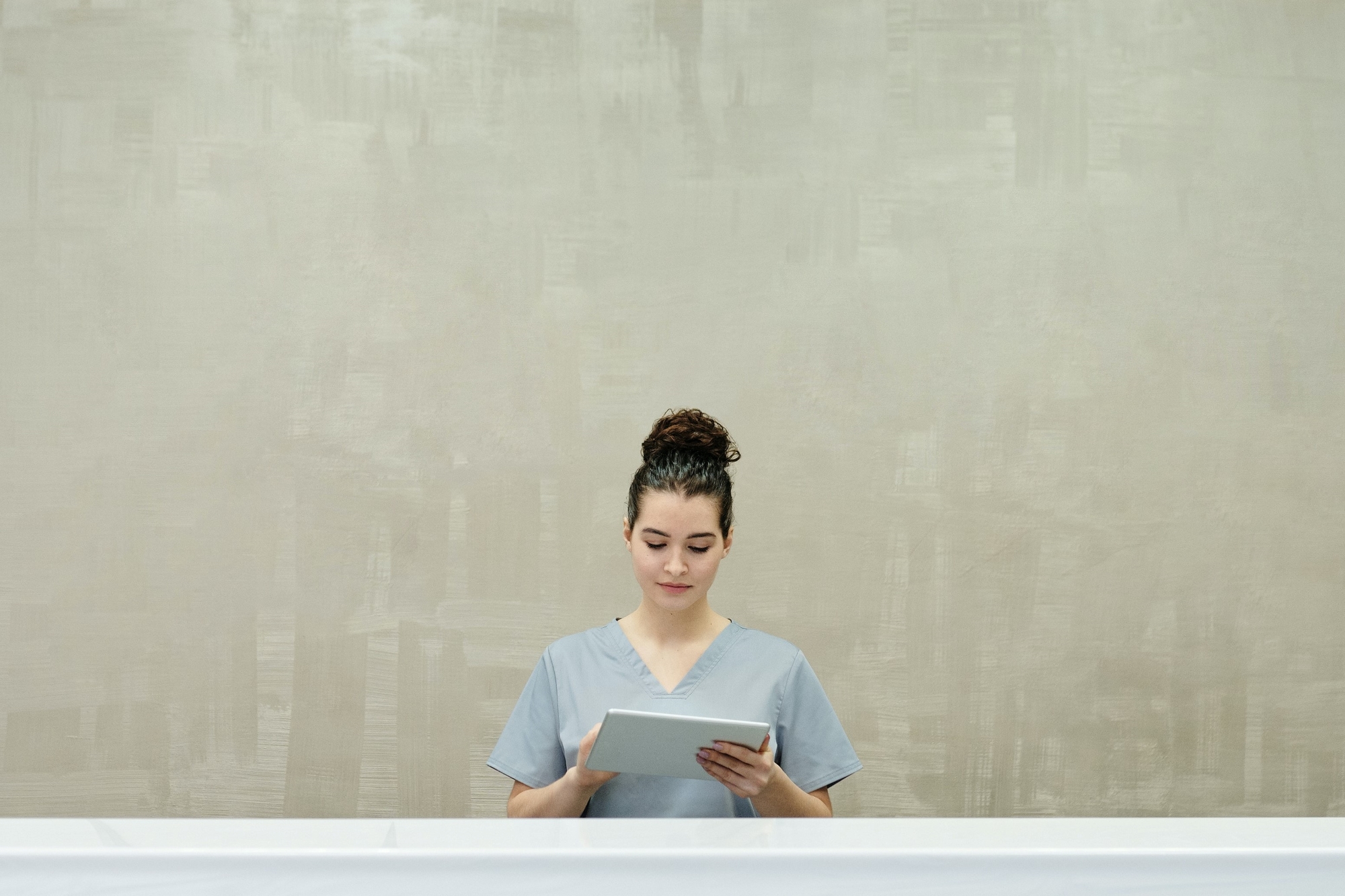 stock image of a woman using a tablet while standing in a hallway