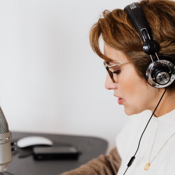 a woman using headphones, singing or speaking into a microphone