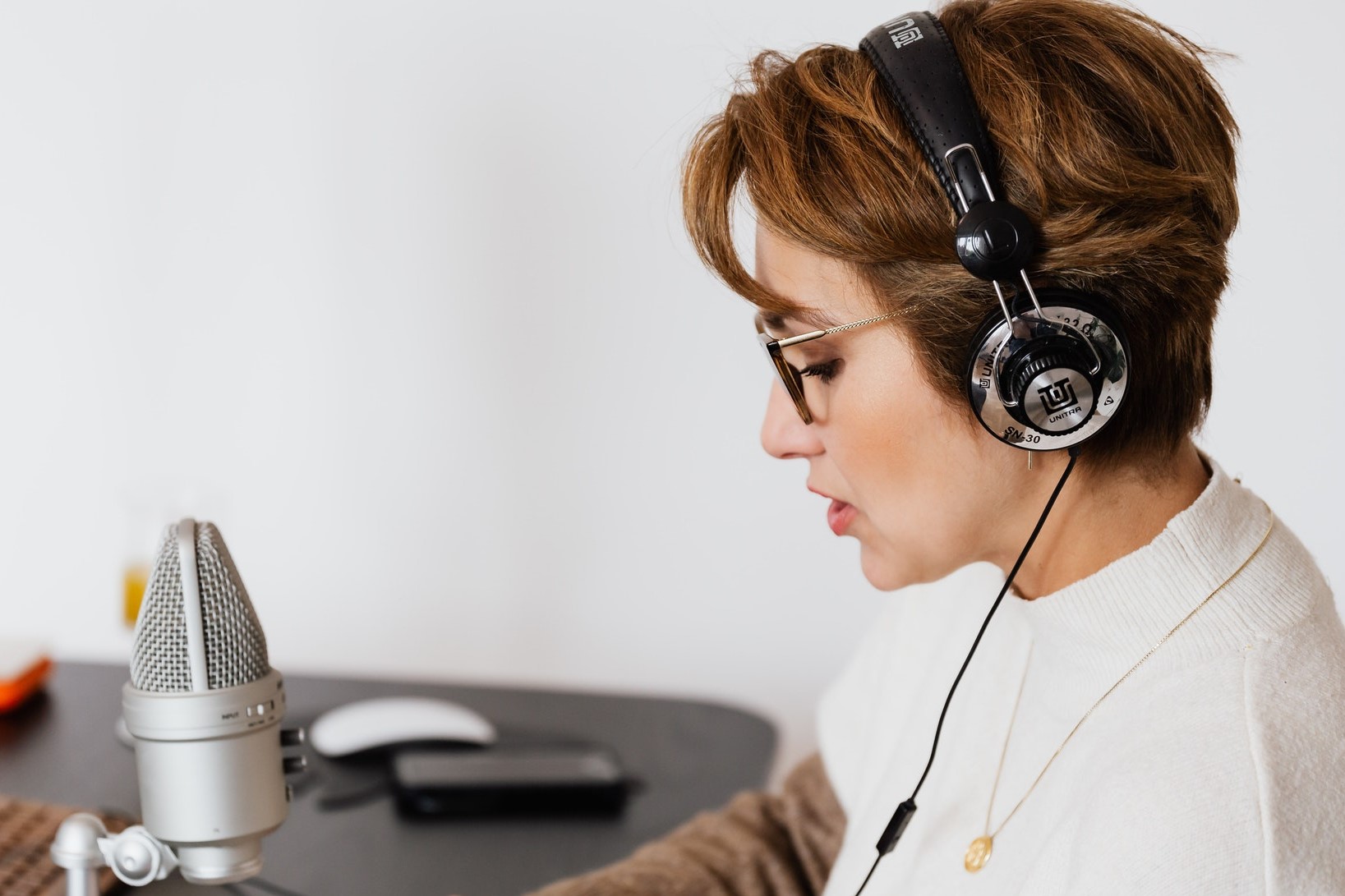 a woman using headphones, singing or speaking into a microphone