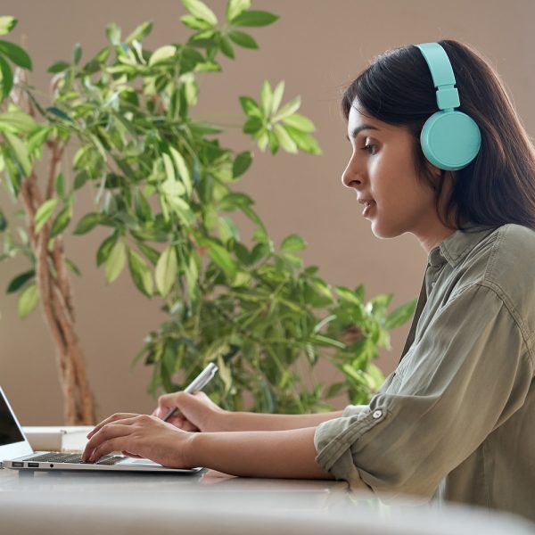 Student wearing blue headphones while using a laptop