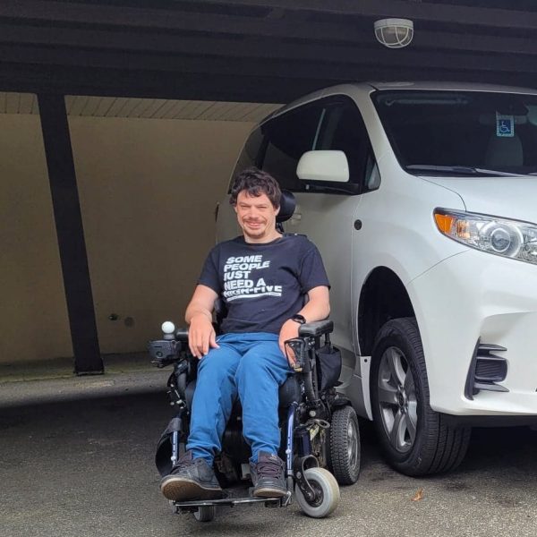 Shayne smiling in front of his modified minivan