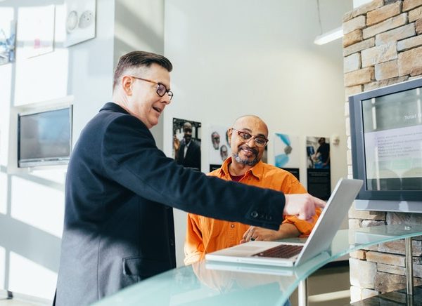 a man points at a computer, while another man looks on