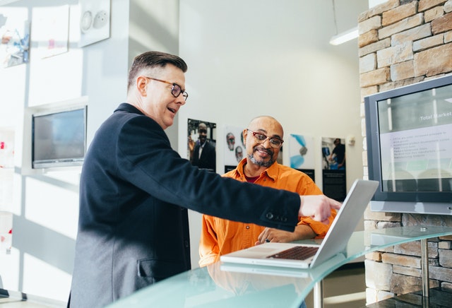 a man points at a computer, while another man looks on