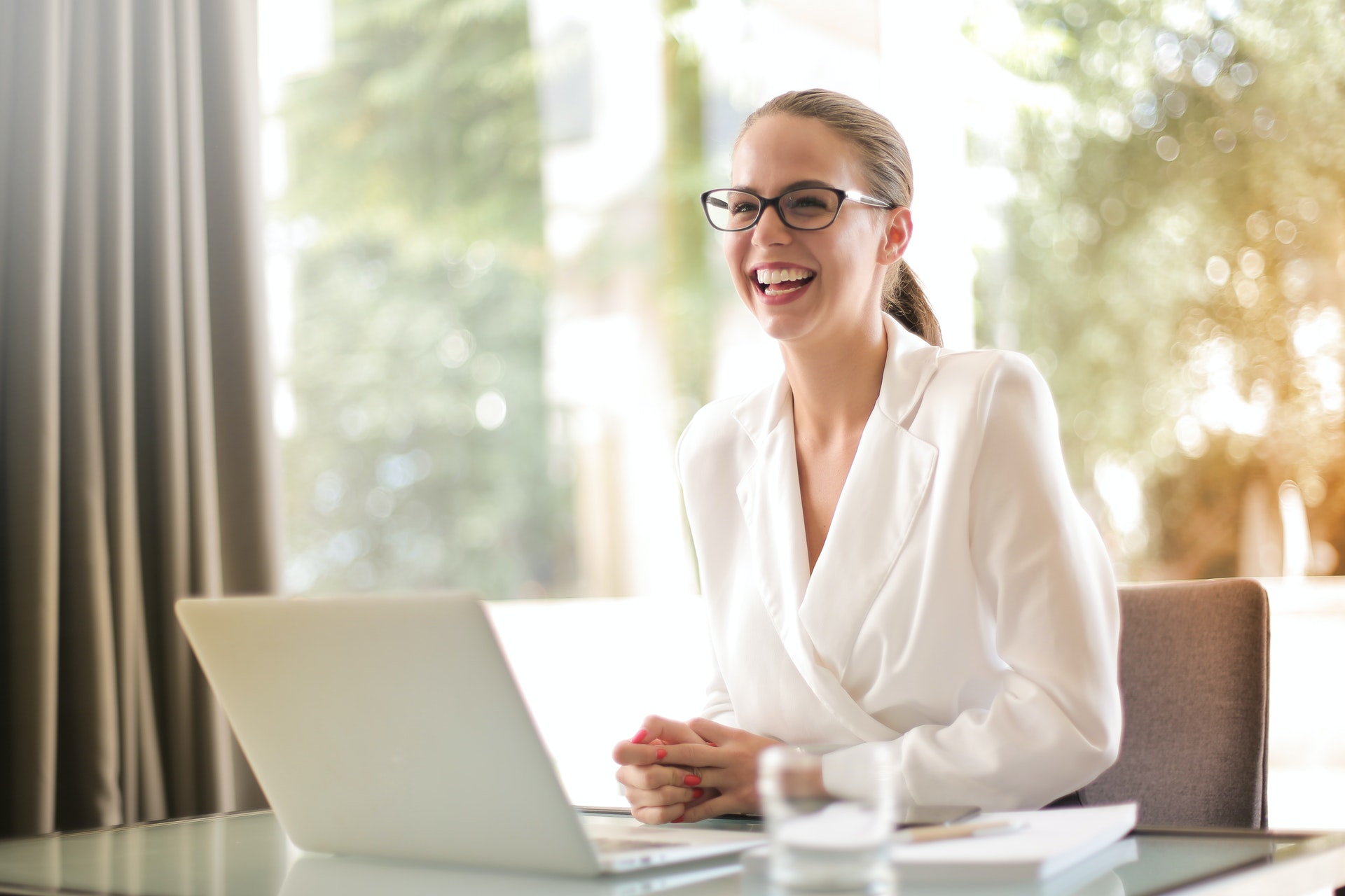 a woman smiling while working on her laptop