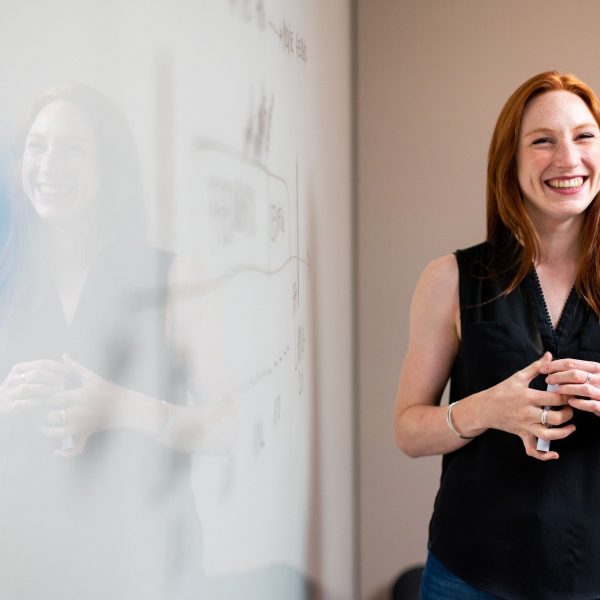 woman smiling while standing near a whiteboard