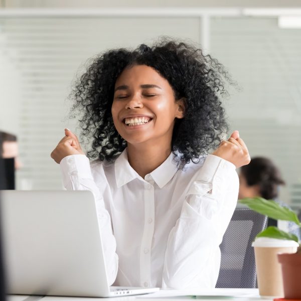 a woman celebrating an achievement while going on the computer