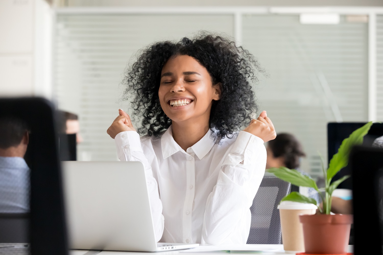 a woman celebrating an achievement while going on the computer