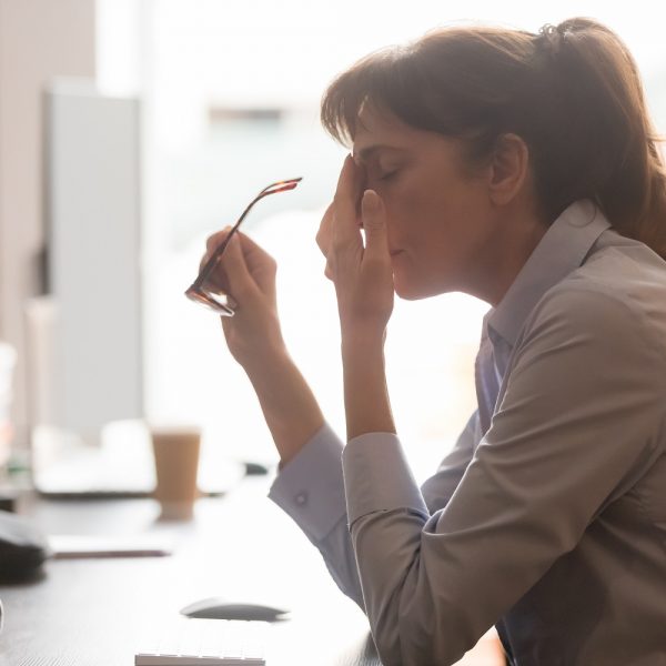 a woman taking off her glasses, with her hand in her face, looking stressed