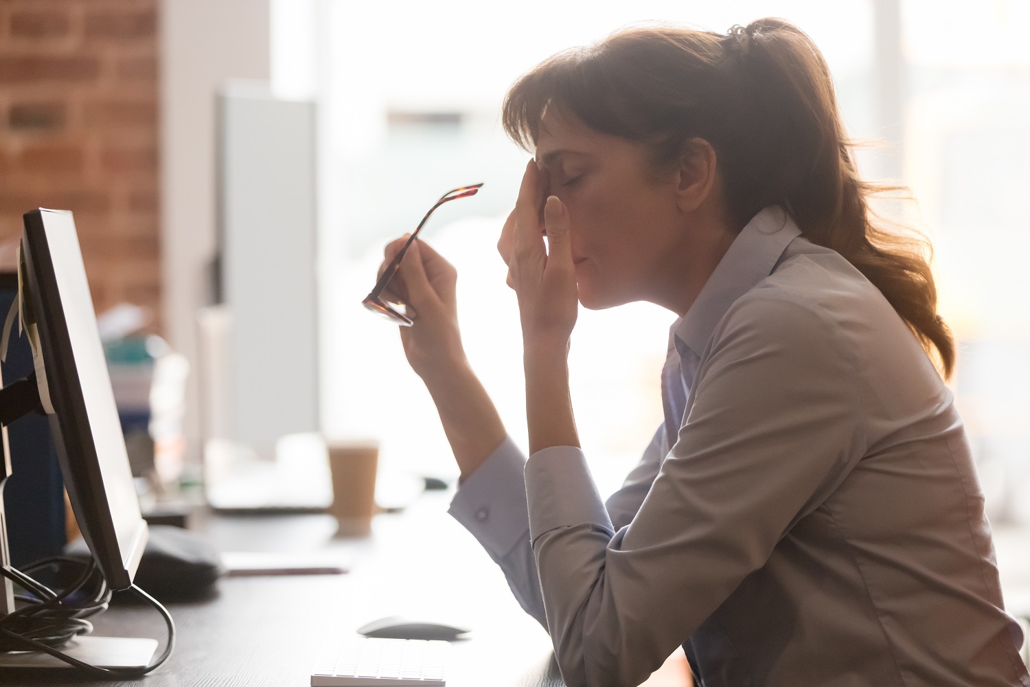 a woman taking off her glasses, with her hand in her face, looking stressed