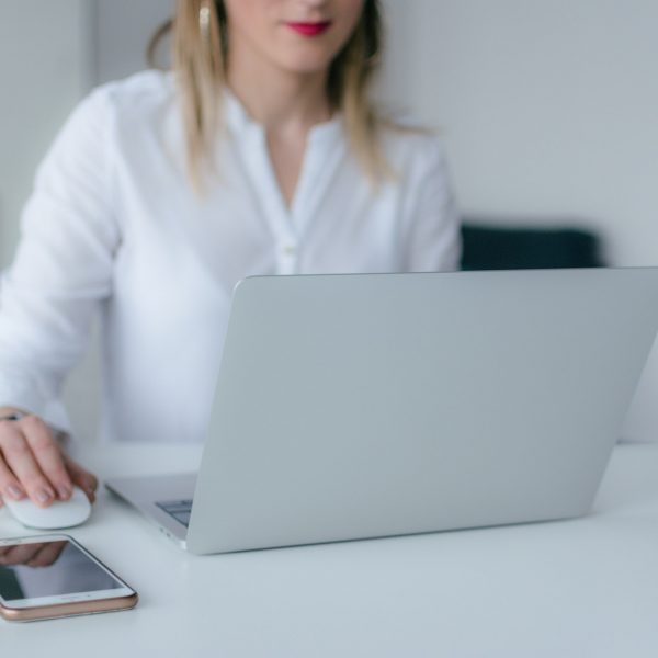 a woman uses her laptop, with her phone nearby on the table