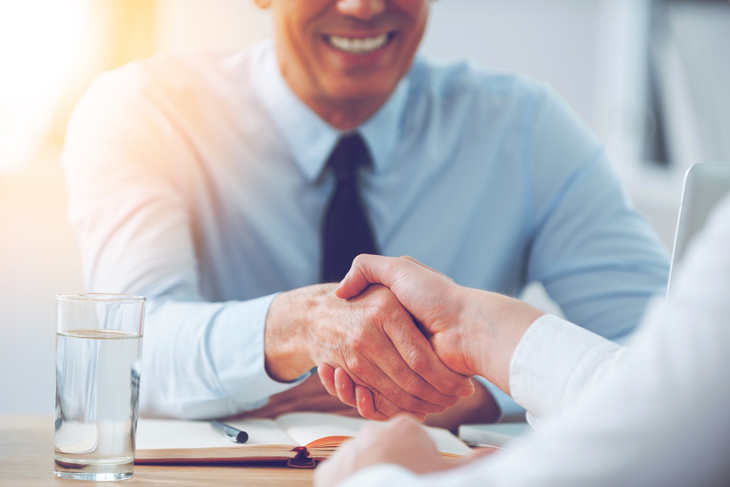 two people shaking hands at the beginning of a job interview