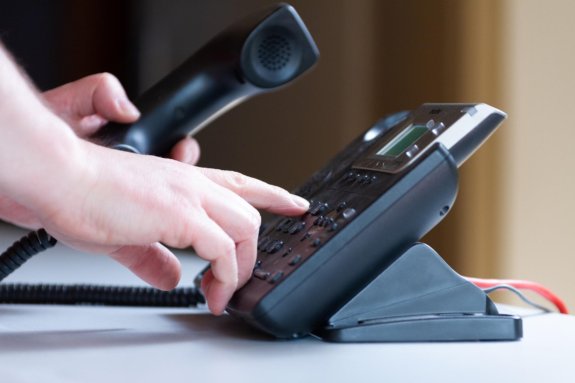 a person dialing an office phone