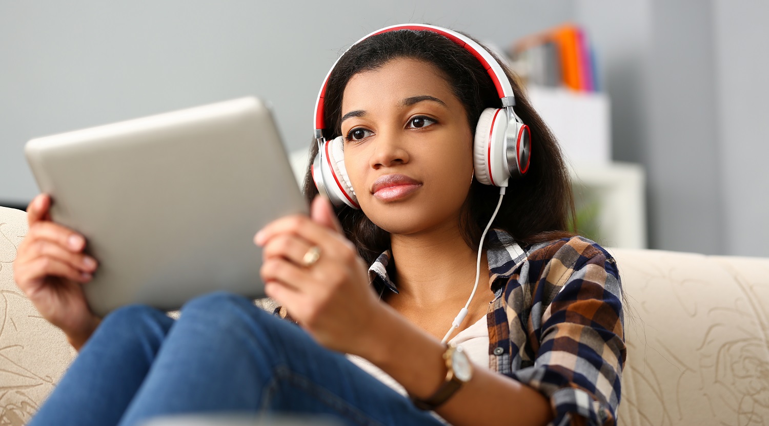 a woman holding a tablet while wearing headphones