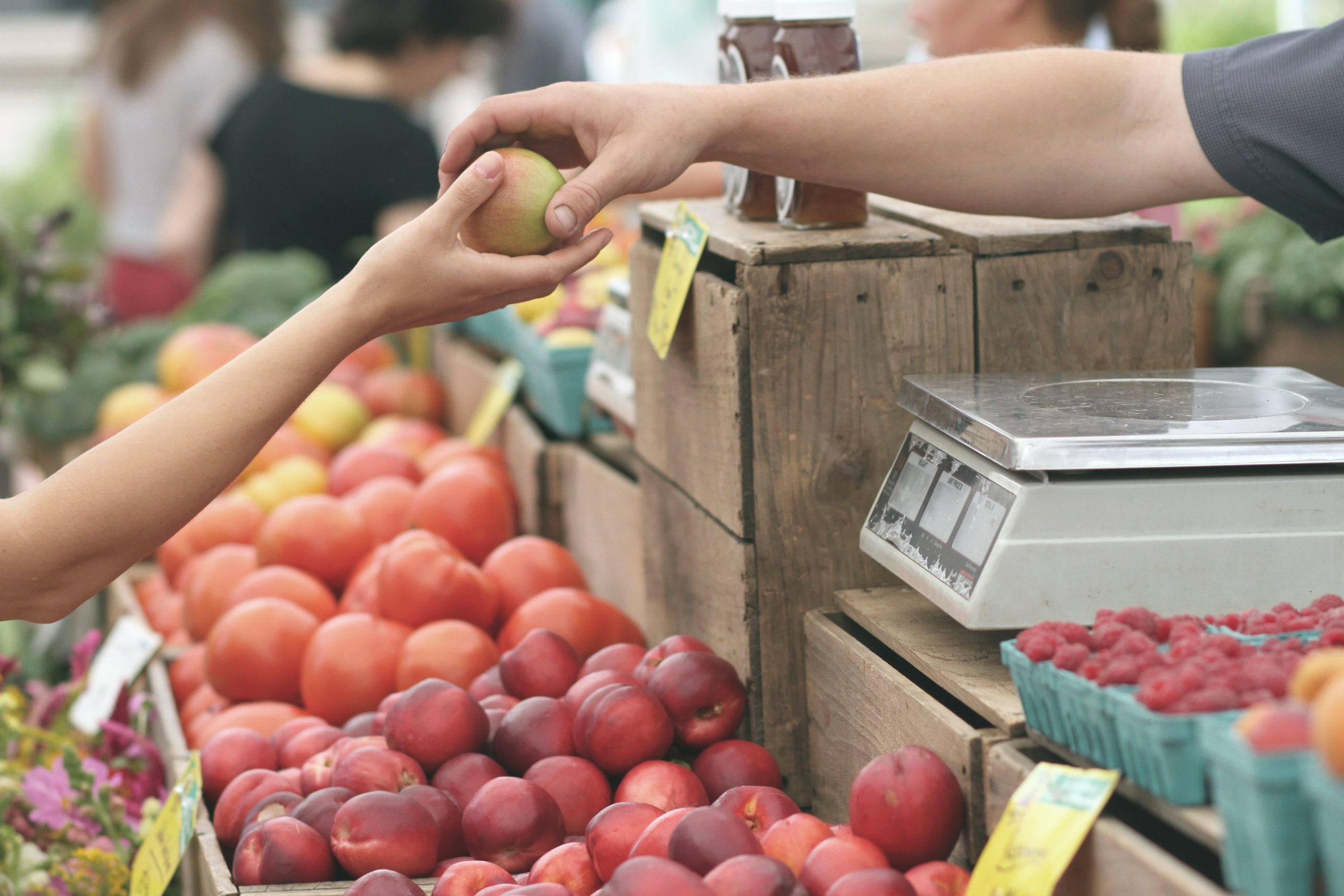 a cashier handing someone a fruit at a farmer's market