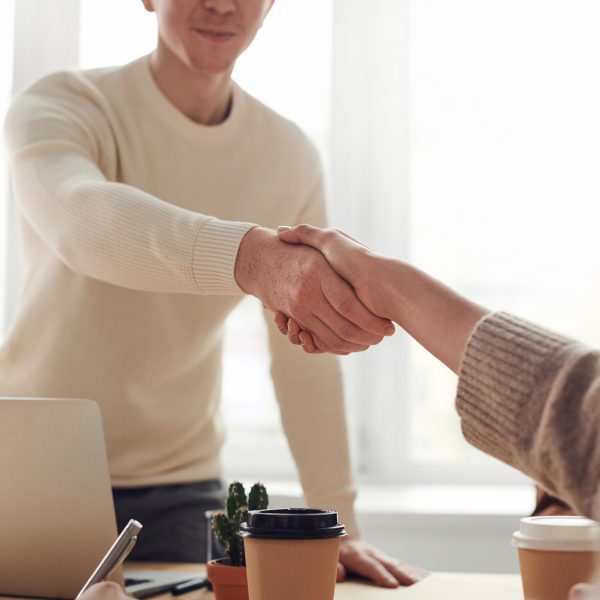 a man behind a desk shaking hands with a person