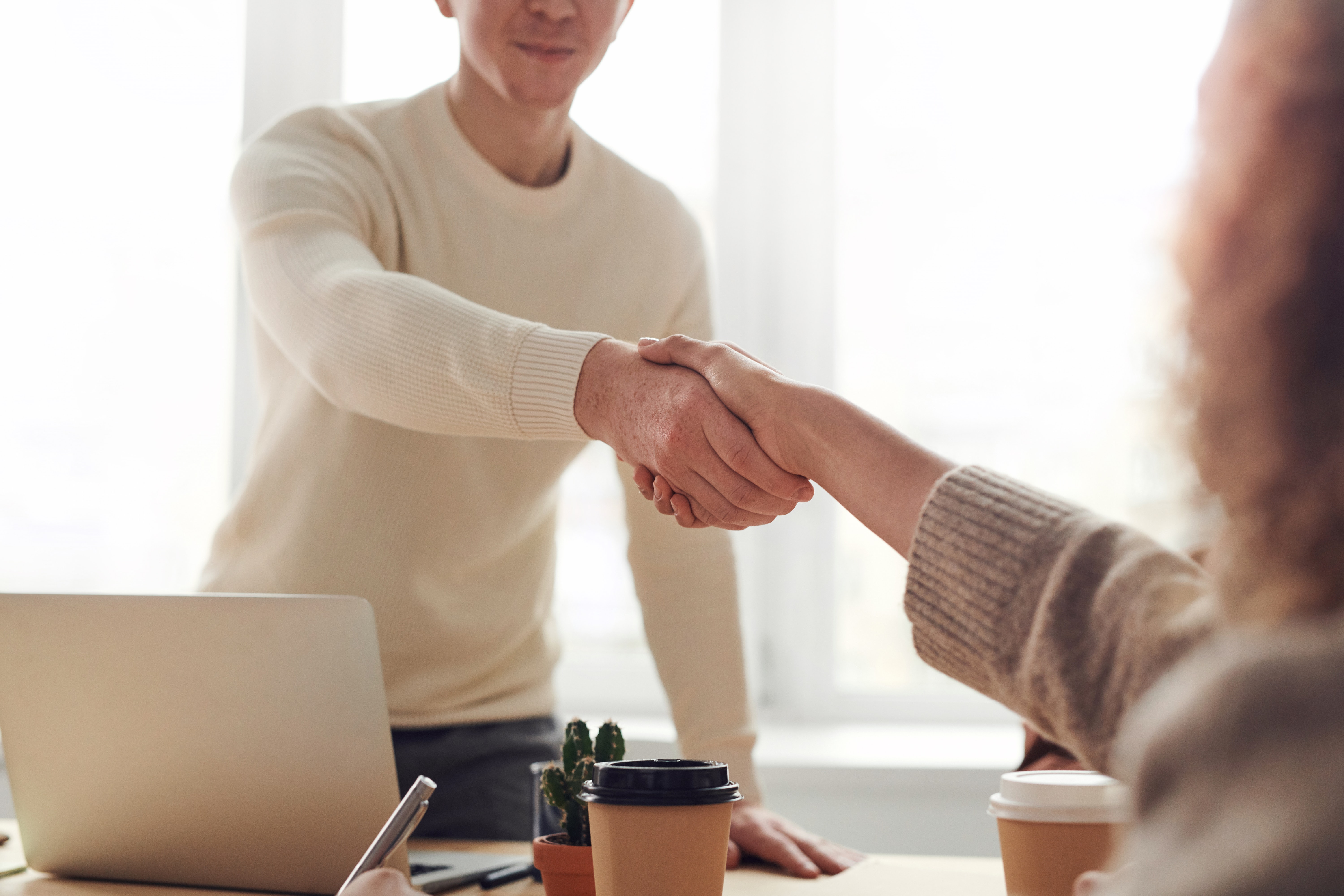 a man behind a desk shaking hands with a person