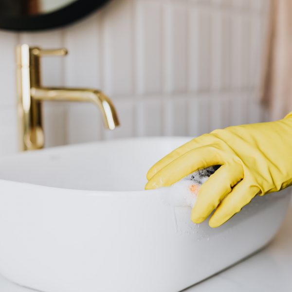 person wearing a glove cleaning a bathroom sink