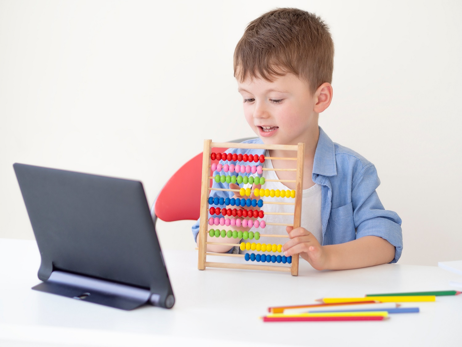 a child playing with an abacus in front of a tablet