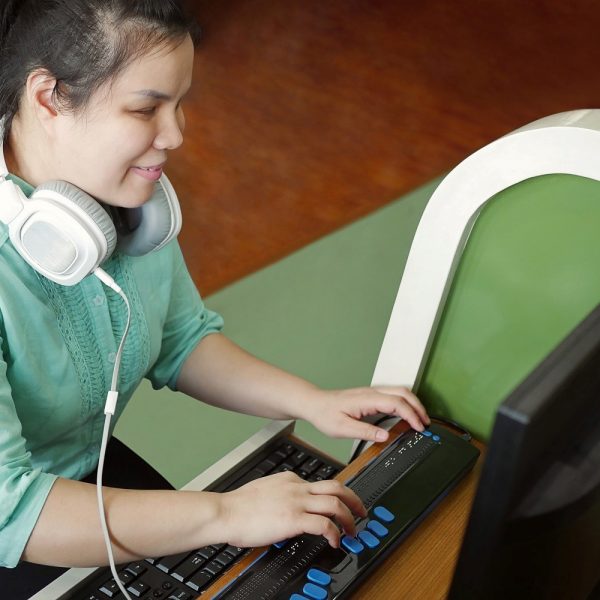 a woman with headphones on her neck using a computer