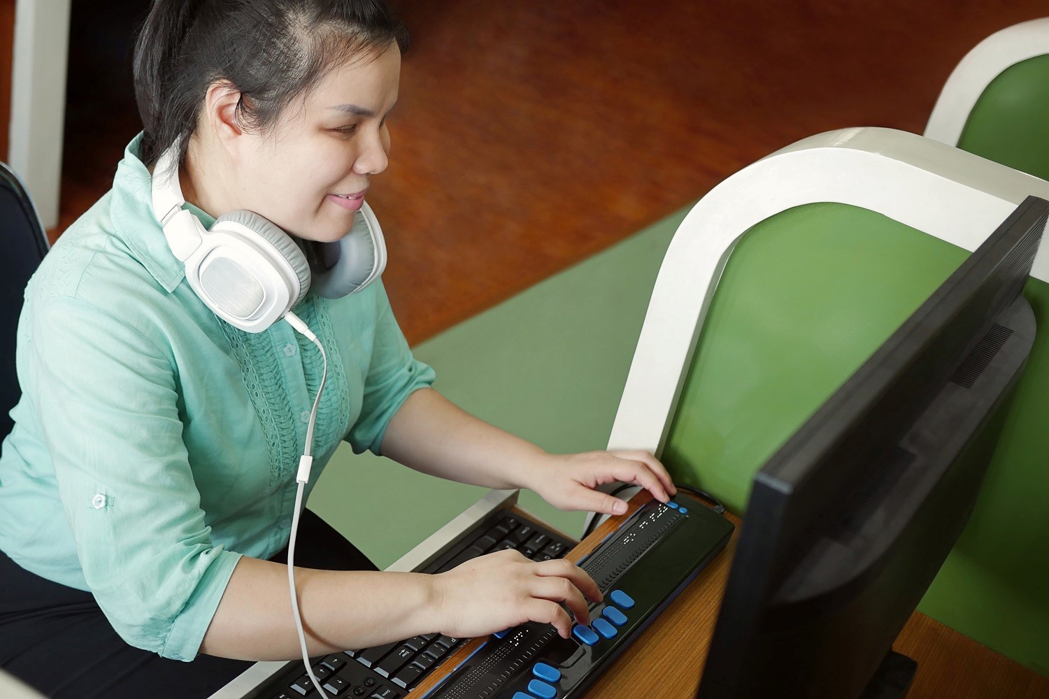 a woman with headphones on her neck using a computer