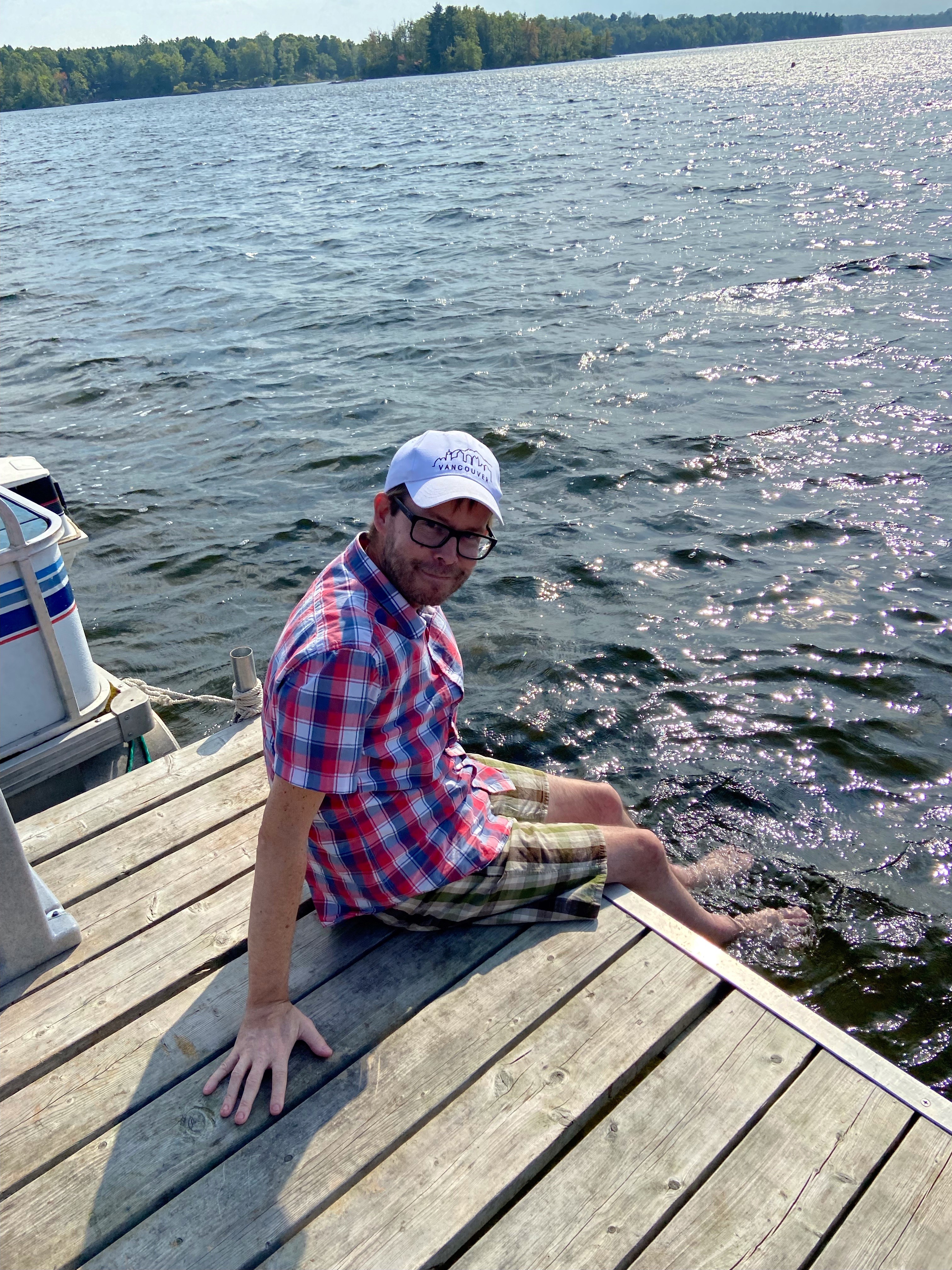 Troy dipping his feet in the lake while sitting on a pier