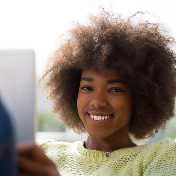 a woman smiling, using a tablet