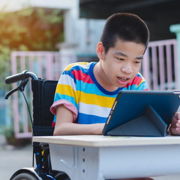 a boy in a wheelchair uses a tablet