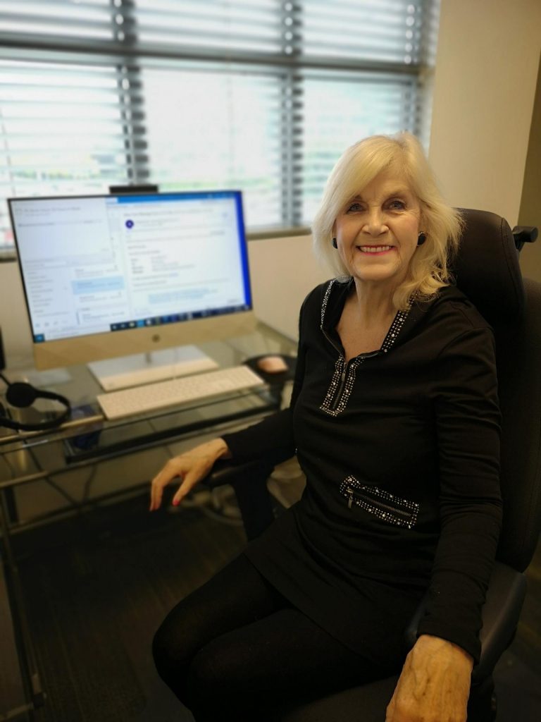 PK sitting in her chair, smiling at her desk