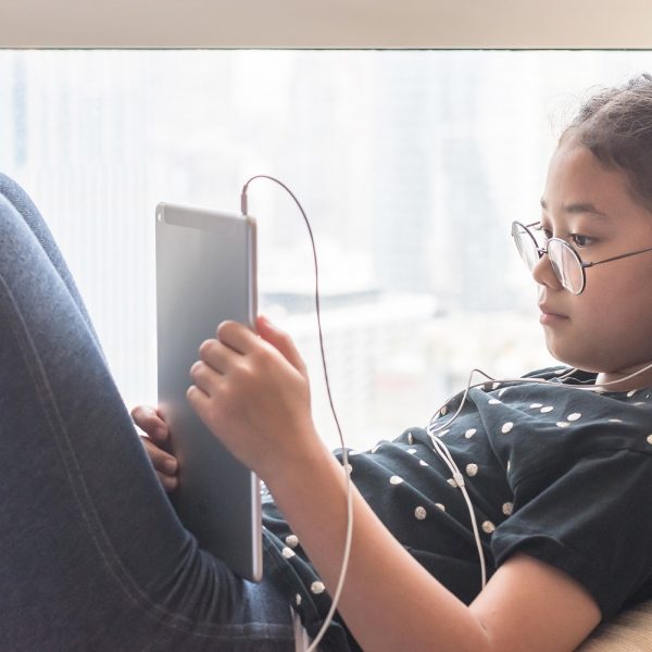 a young girl is looking at a tablet with her headphones in