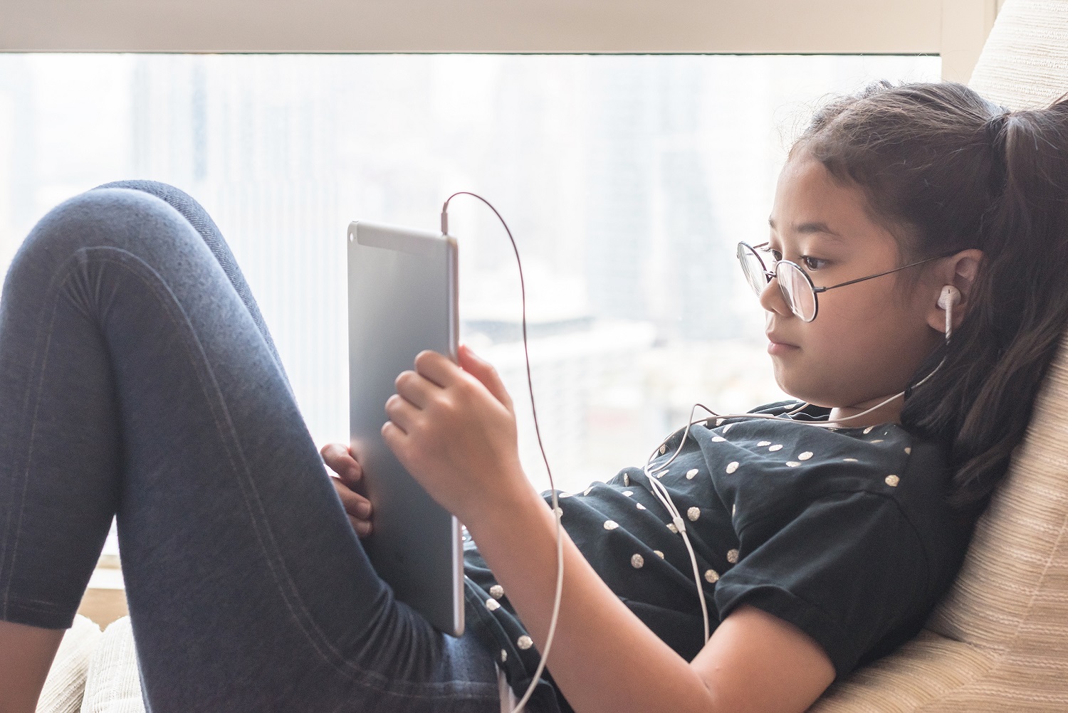 a young girl is looking at a tablet with her headphones in