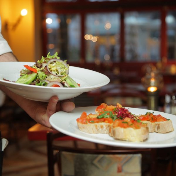 a waiter holds two plates with food on them